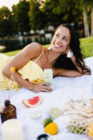 Woman drinking Hibiscus Vanilla SkinTe outside at a picnic.